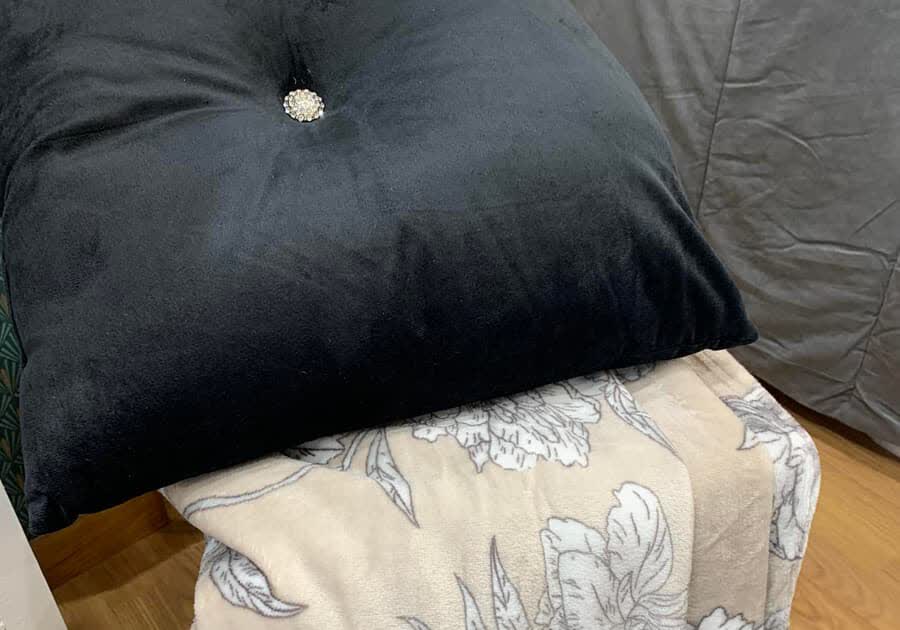 Cojín de terciopelo negro sobre colcha estampada en Lugo