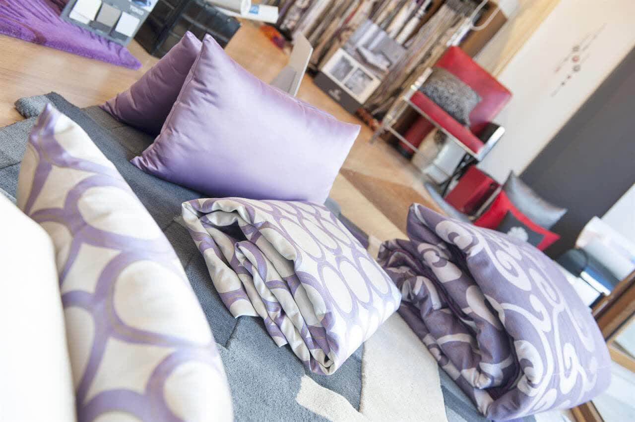 Cojines estampados en tonos lila combinados con ropa de cama en Lugo