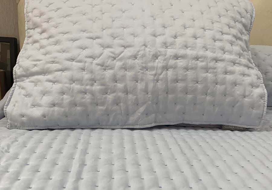 Edredón acolchado gris claro sobre una cama en Lugo