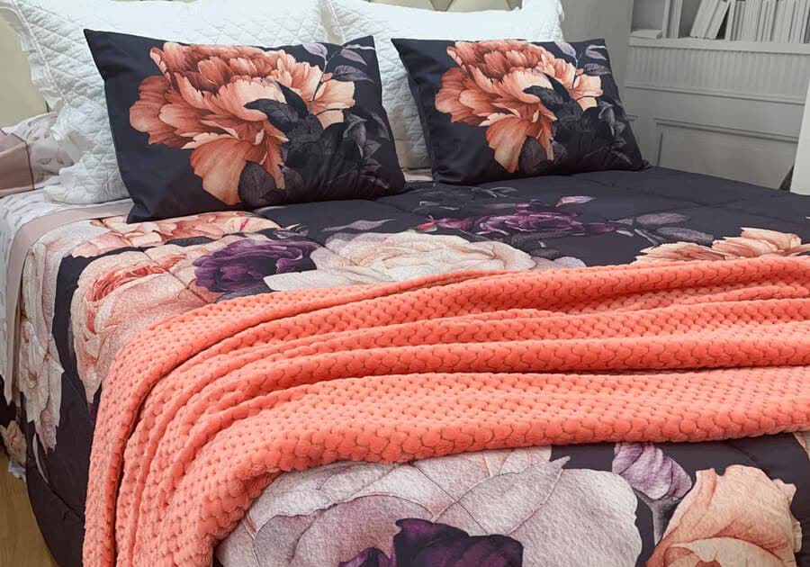Plaid de punto coral a los pies de una cama con flores en Lugo